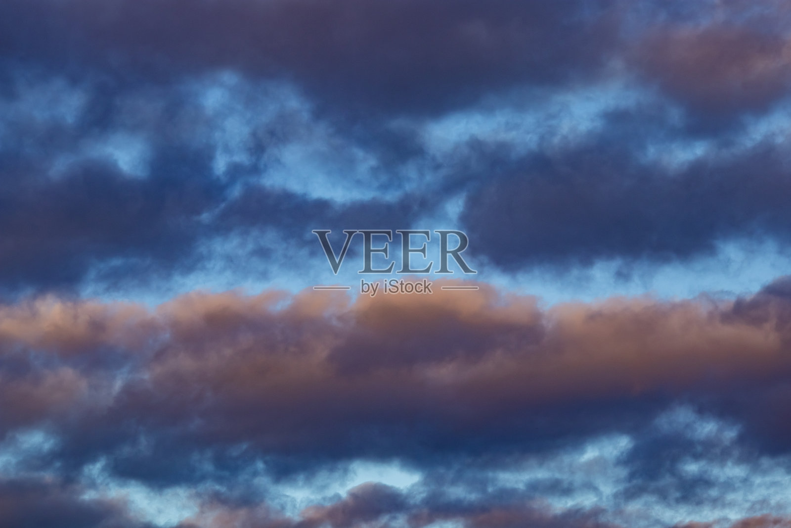 戏剧性的晚间云彩在蓝天映衬下被温暖的光线染色,位于英格兰梅西萨德的威勒尔。照片摄影图片