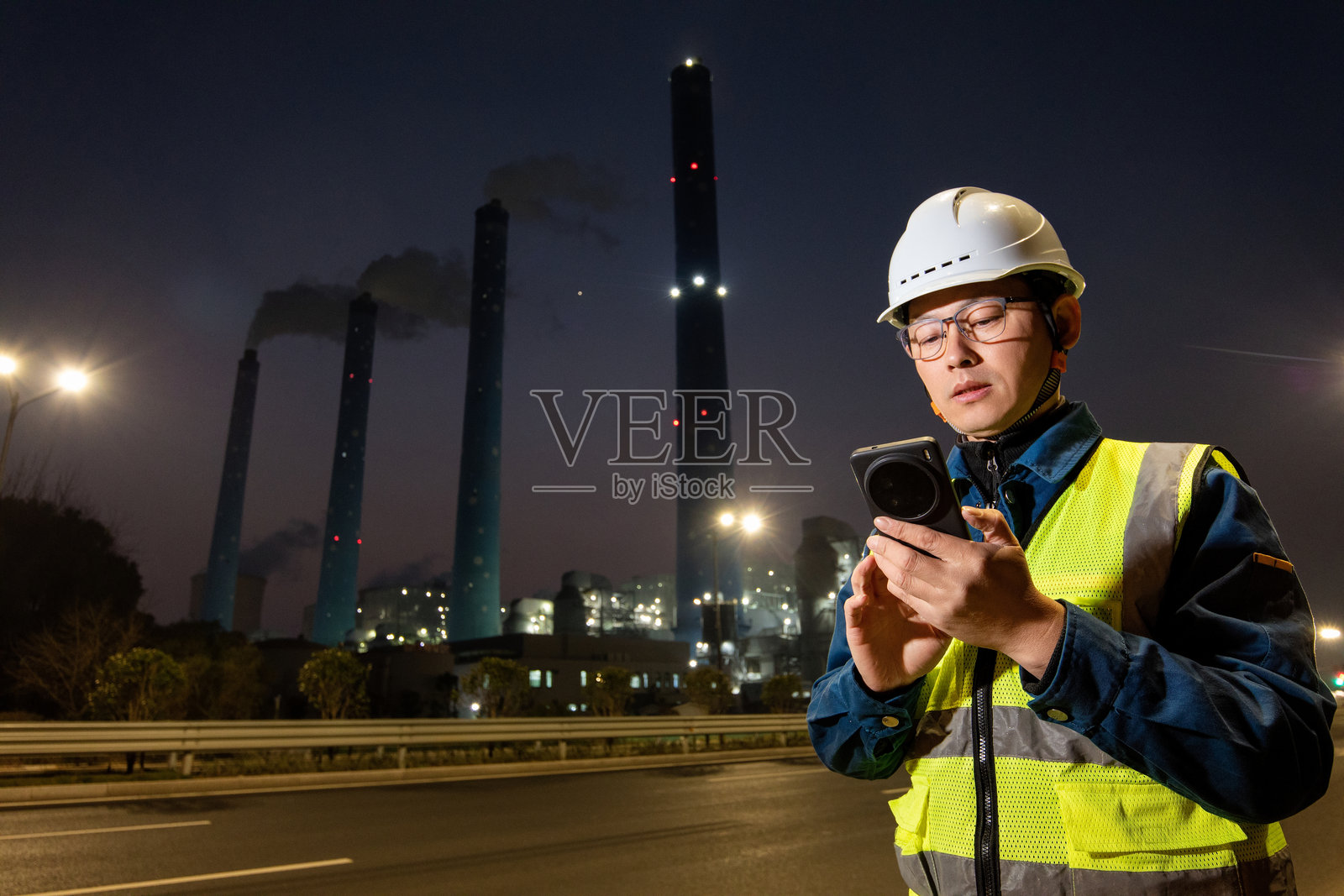 中年男性工程师在火力发电厂使用智能手机照片摄影图片