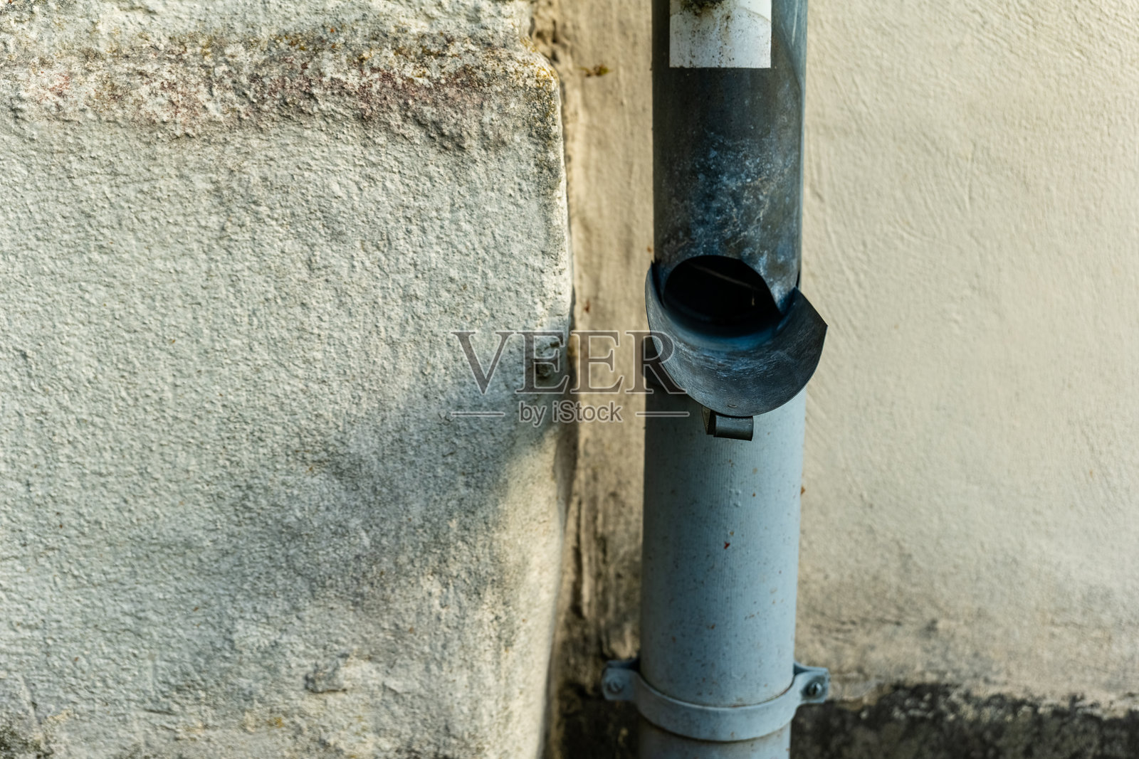 乡村风格的排水管靠在一面陈旧的墙壁上,静谧小巷中,捕捉到日落时分城市衰败的美感照片摄影图片