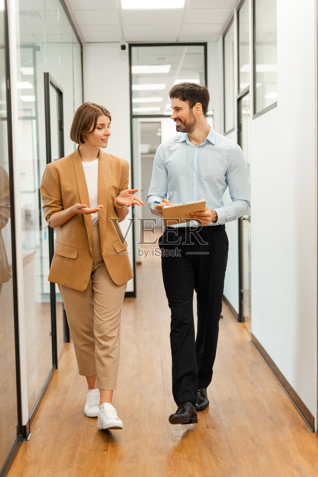 商务同事在办公室走廊里边走边谈照片摄影图片