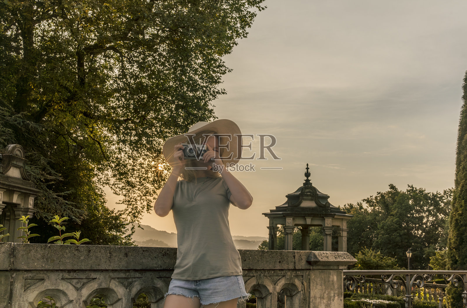 一位戴着草帽的年轻女性正在用一台非常古老的复古相机拍照照片摄影图片