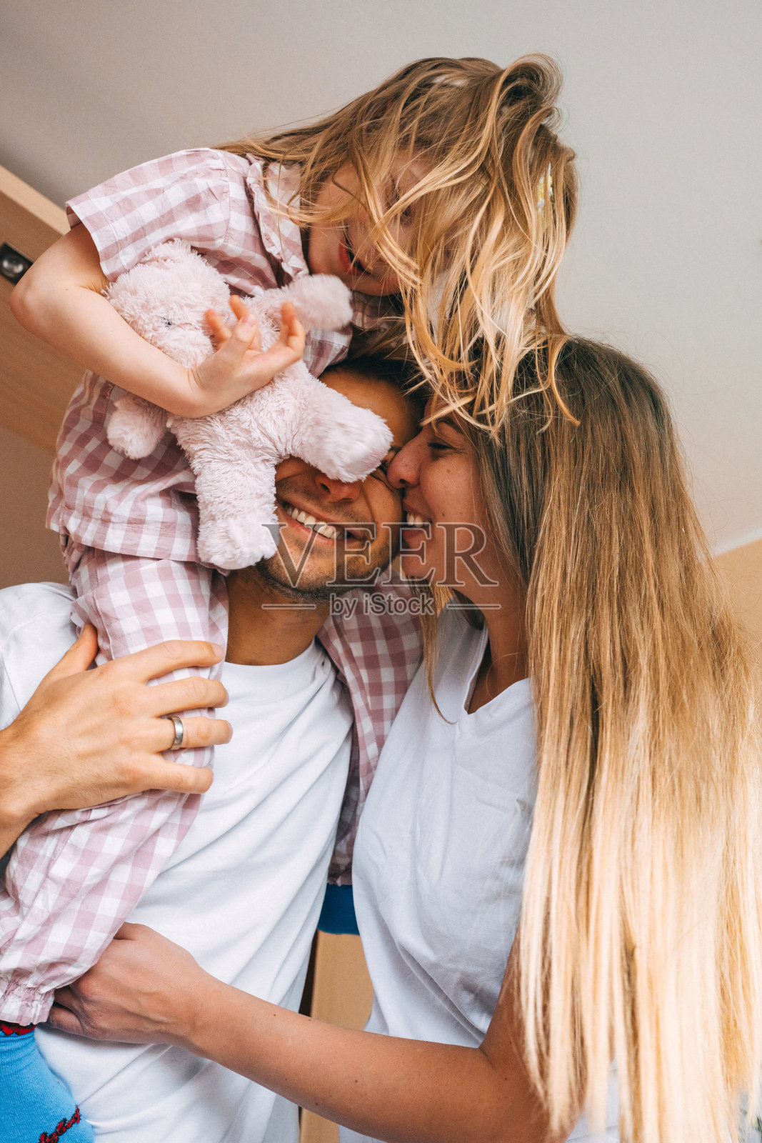 温馨的家庭在室内与女儿享受轻松愉快的时光,大家穿着休闲服装。照片摄影图片