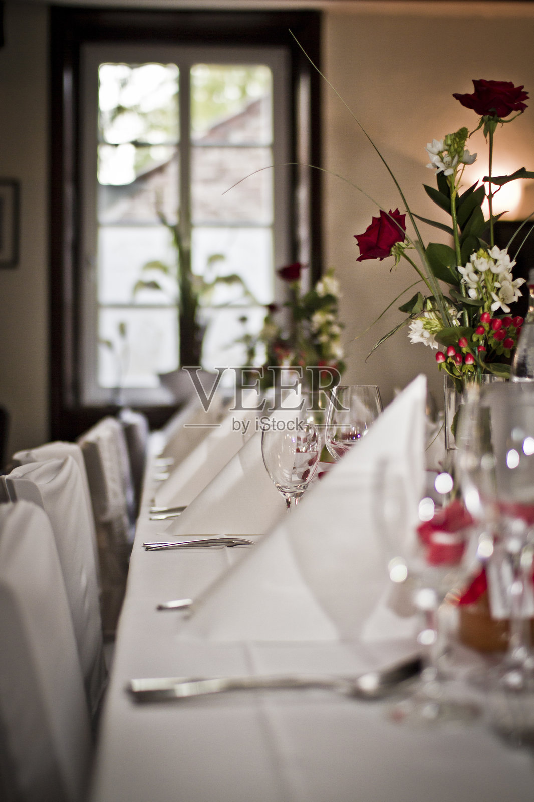 优雅的餐桌布置,装饰着玫瑰和节日装饰,营造出温馨的餐厅氛围照片摄影图片