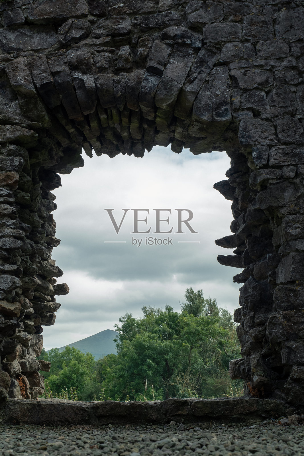 在历史遗址的阴天,探索俯瞰郁郁葱葱绿意的古老石拱门照片摄影图片