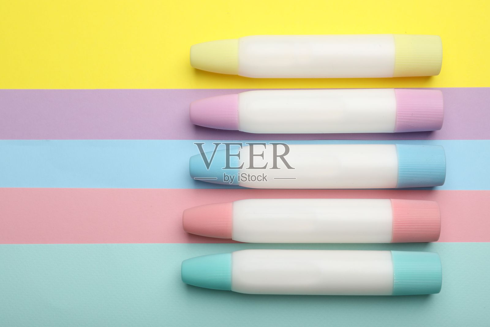 彩色背景上的胶棒,平铺展示照片摄影图片