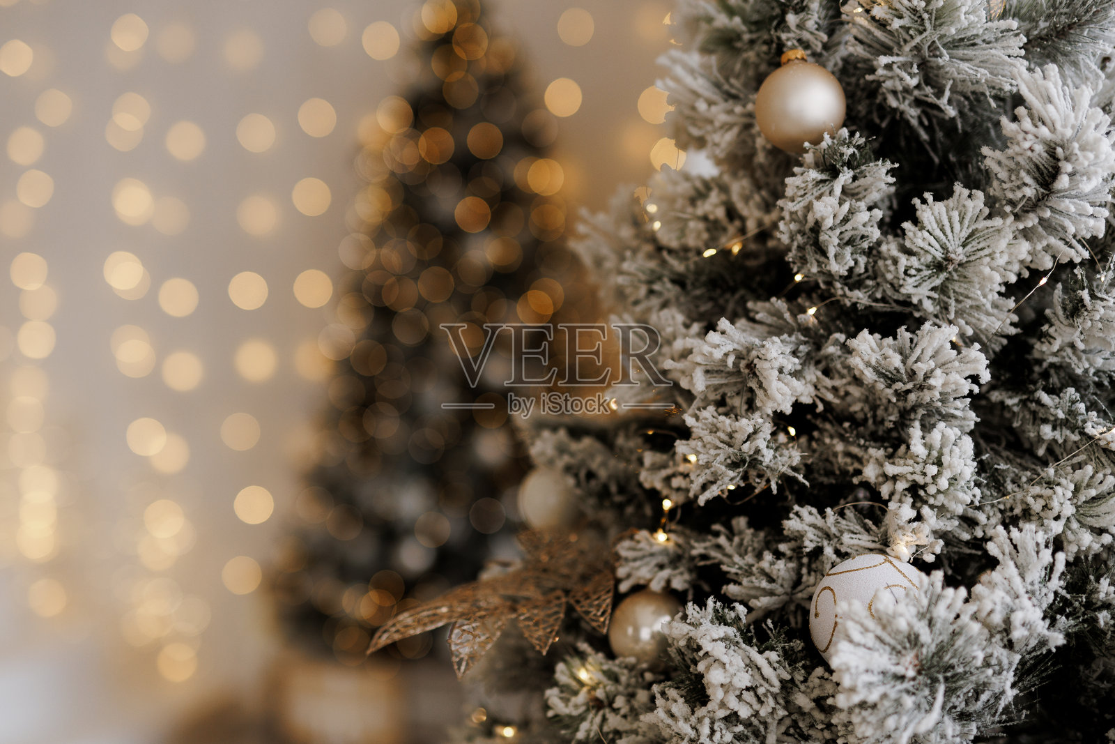 装饰华丽的圣诞树特写,雪覆盖的树枝和金色装饰品,背景模糊的节日灯光照片摄影图片