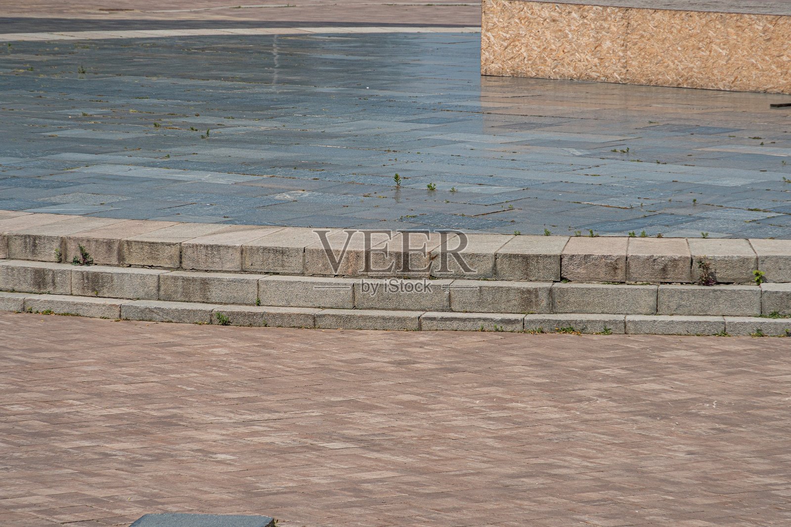 宁静的户外场景,弯曲的砖石小径和风化的灰色石墙,棕色、米色和灰色的对比瓷砖区域,柔和的散射光线,柔和的自然色彩照片摄影图片