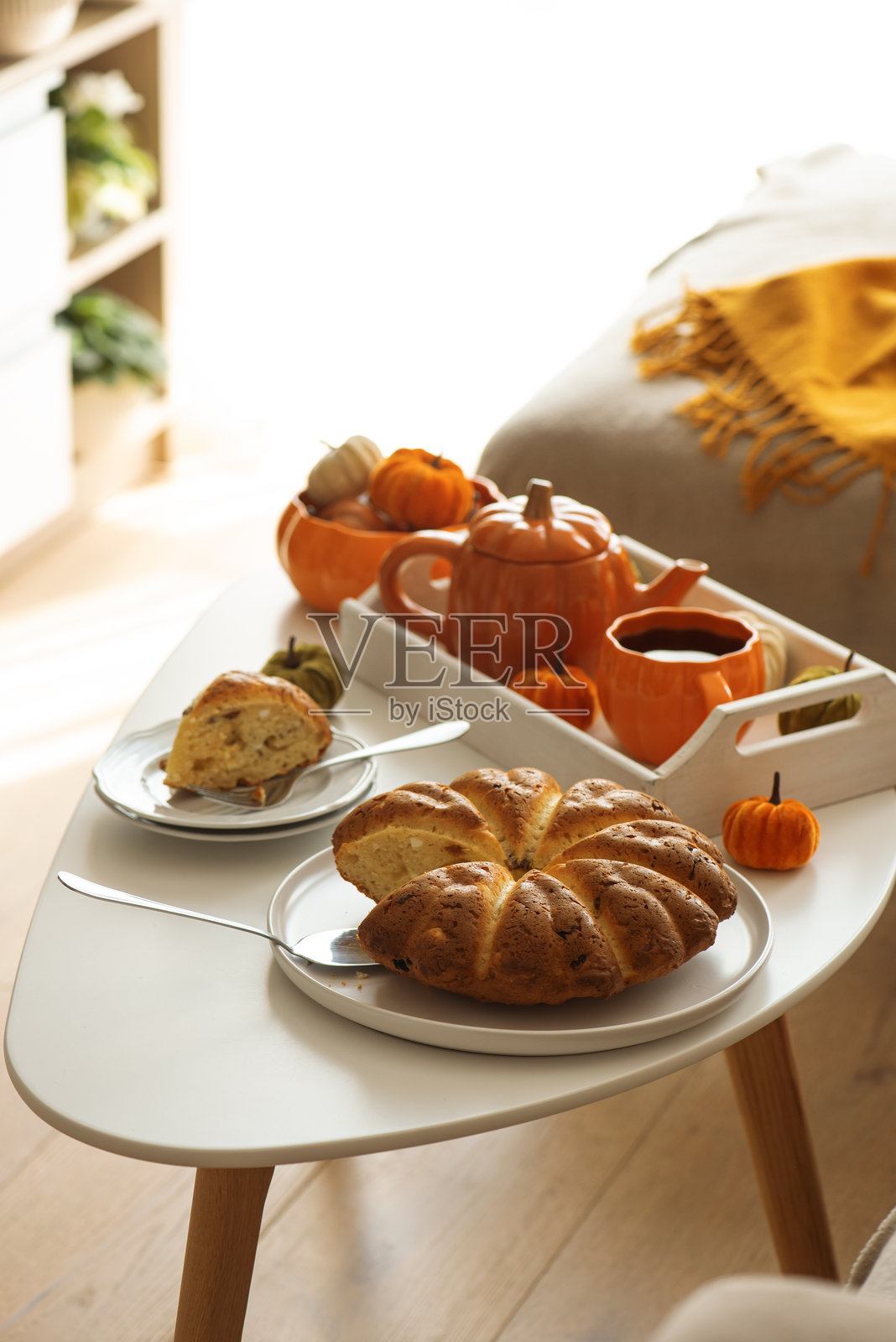 秋季客厅装饰,摆放着南瓜、茶具和蛋糕。照片摄影图片