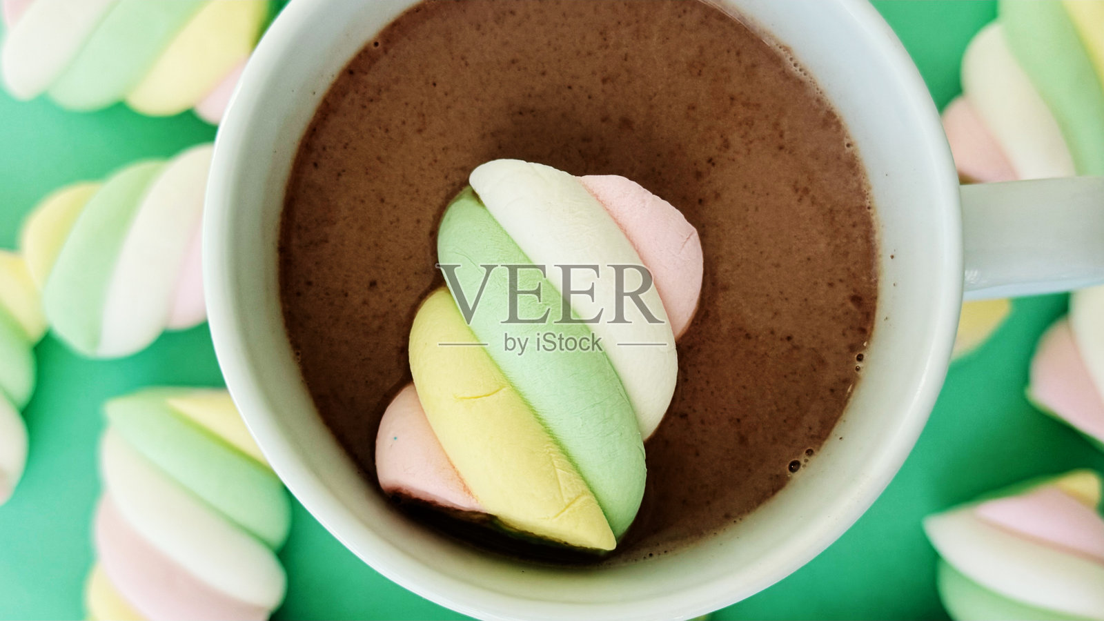 绿色背景上白色杯子里的彩色棉花糖可可饮品特写 — 甜点纹理样机,留有空白空间照片摄影图片