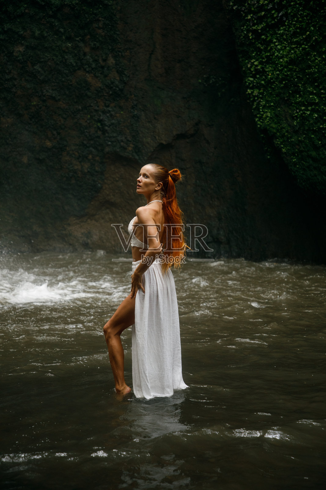 女人站在流动的水中,四周环绕着绿色自然和宁静的风景照片摄影图片