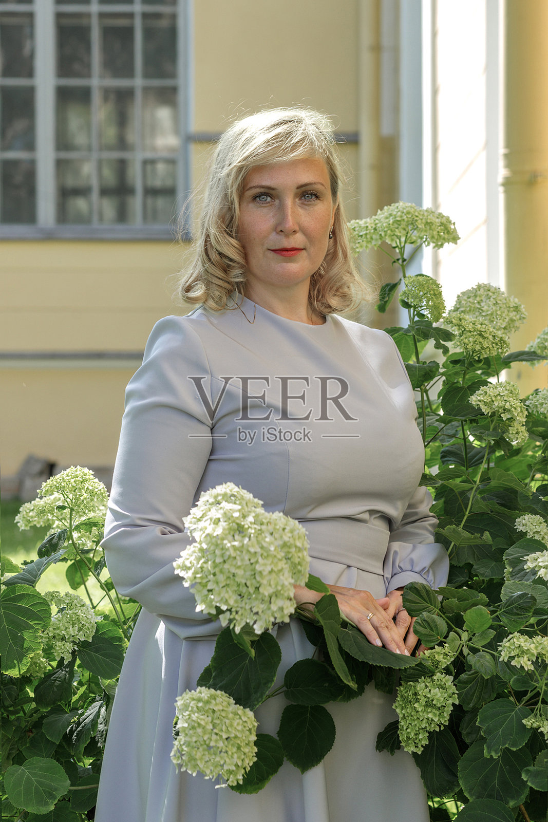 年轻女子穿着复古蓝色连衣裙,在夏季公园中漫步。照片摄影图片