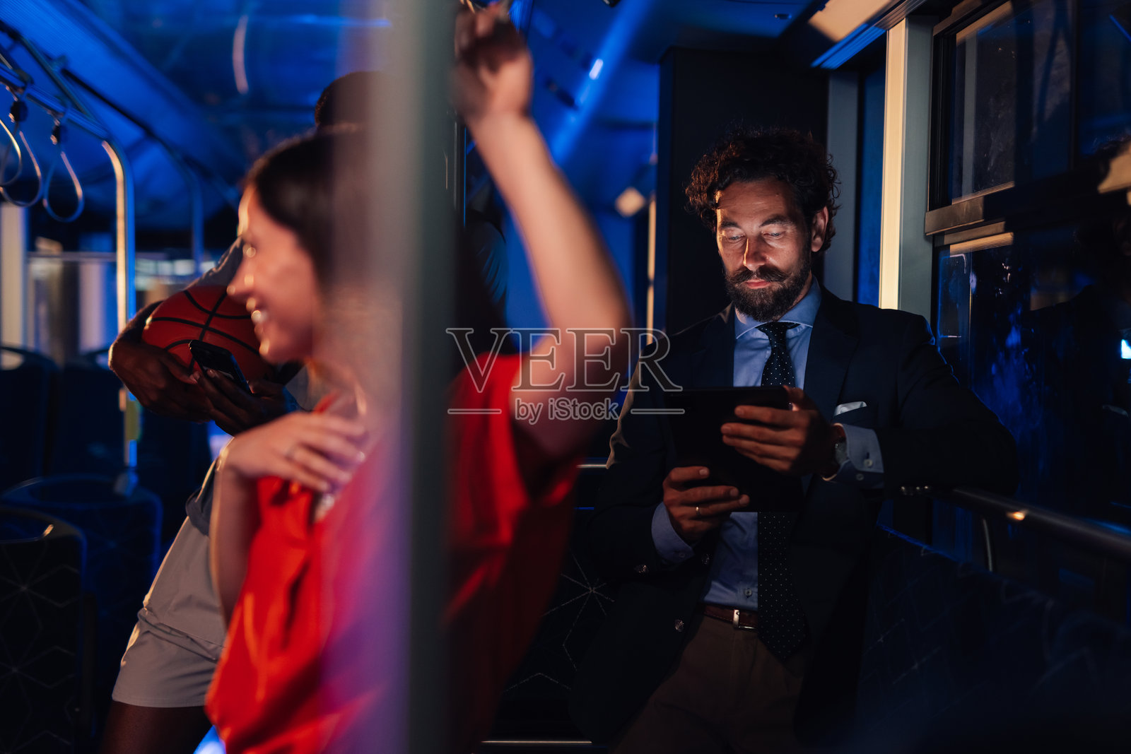 商人在夜间公交通勤时使用数字平板电脑照片摄影图片