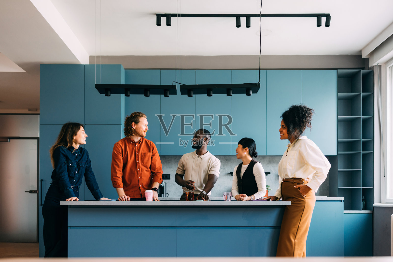 多元化的朋友们在明亮现代设计的厨房里交谈照片摄影图片