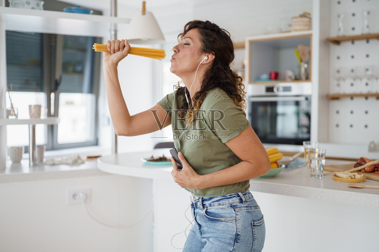 年轻女性在明亮现代的厨房中快乐地唱歌跳舞照片摄影图片