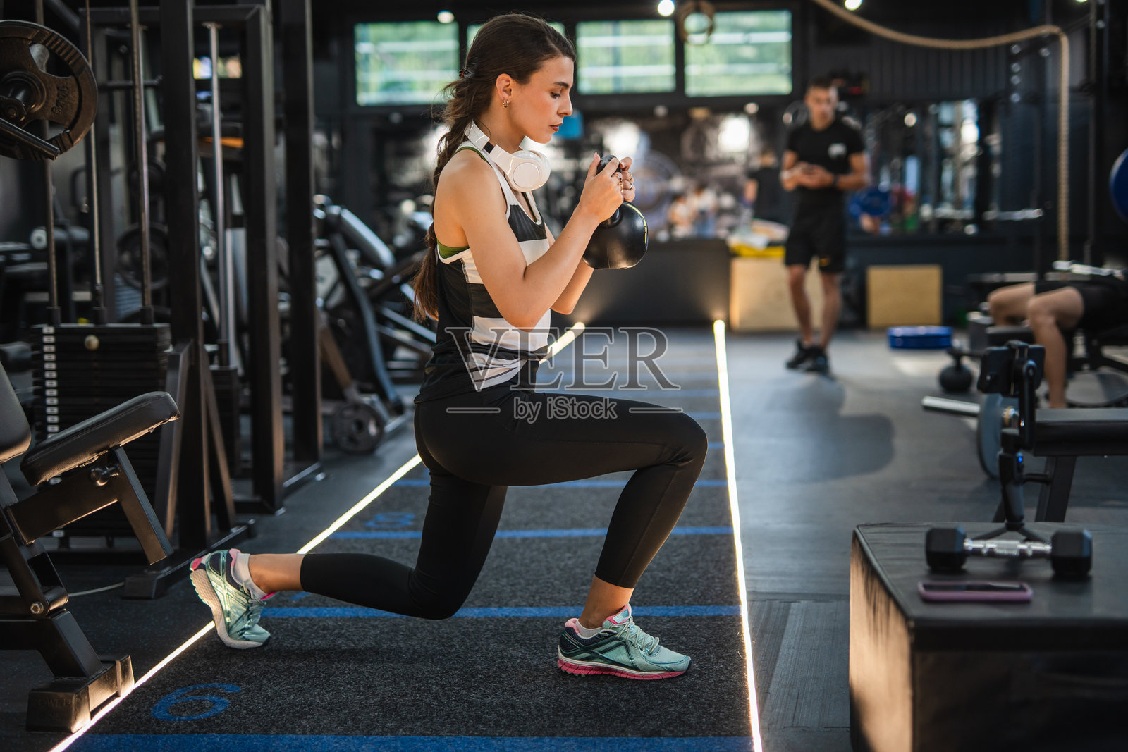 专注的成年女性在健身房使用壶铃锻炼照片摄影图片