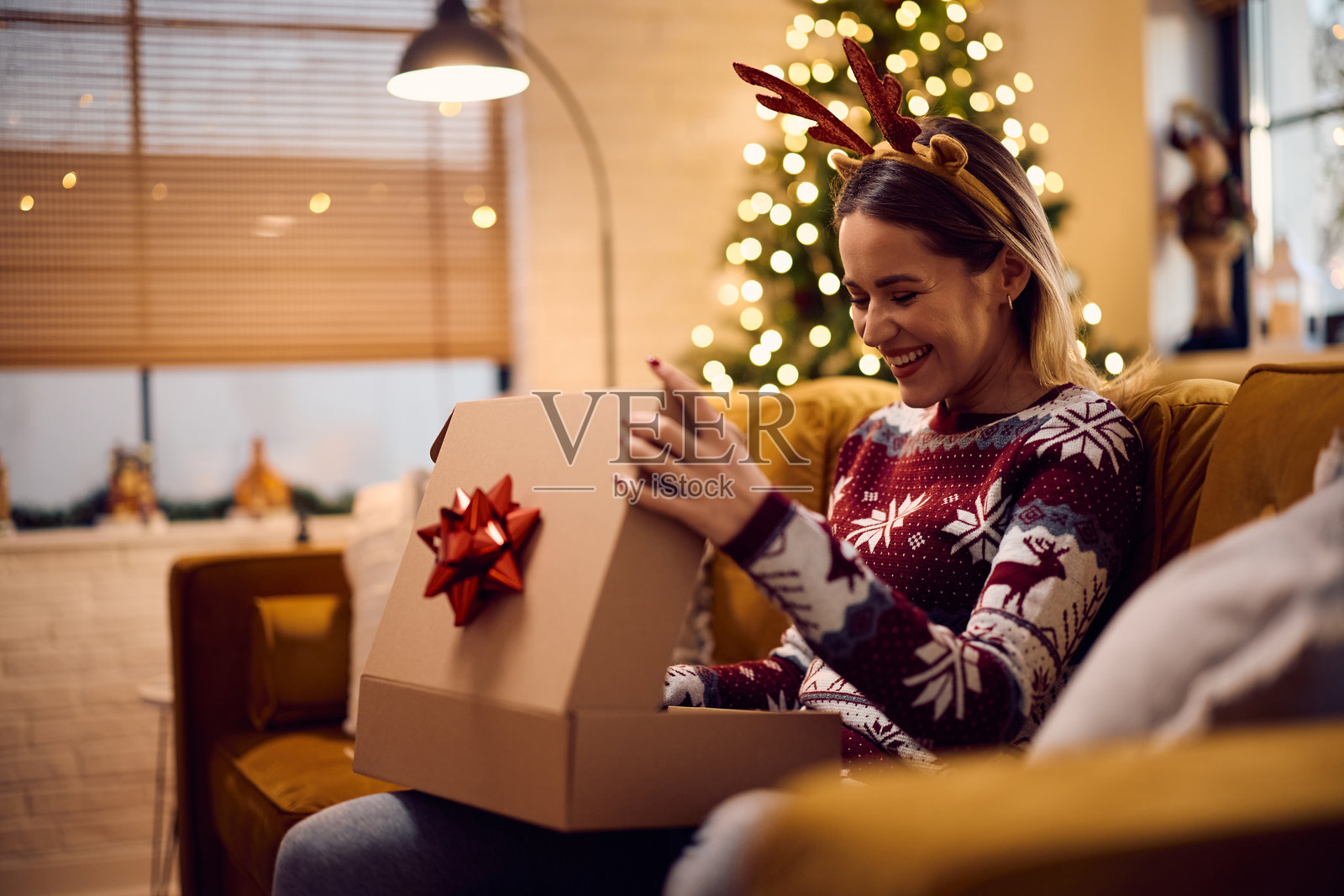 快乐的女人在家中享受打开圣诞礼物的时刻。照片摄影图片