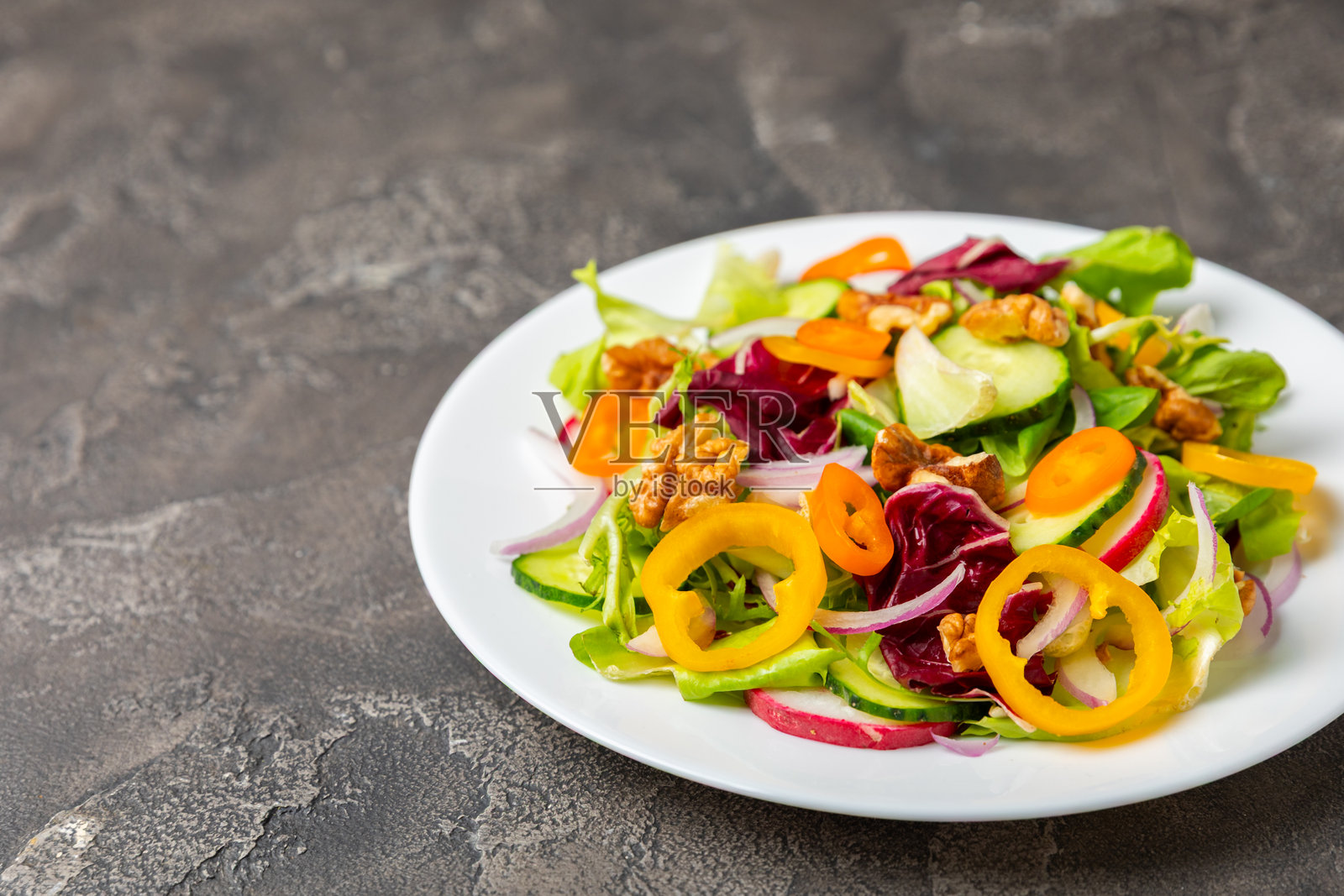 木质背景上的黄瓜沙拉。自制沙拉,盘中有新鲜蔬菜、黄瓜、西红柿、甜椒和生菜。素食春季沙拉。素食饮食。健康饮食。留白以便添加文字。照片摄影图片