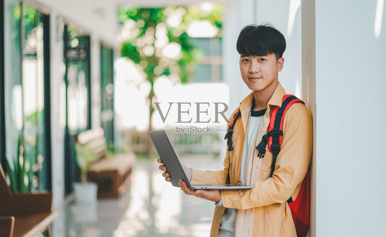 手拿书本的快乐微笑学生在校园里走去,准备学习。照片摄影图片