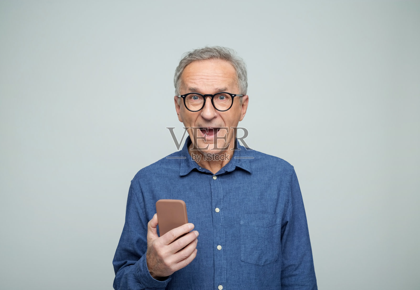 惊讶的老年男子使用手机的肖像照片摄影图片