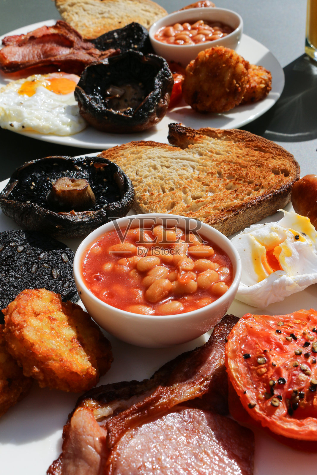 丰盛的英式煎早餐,包含烤豆、番茄、荷包蛋、吐司、培根、蘑菇和土豆饼照片摄影图片