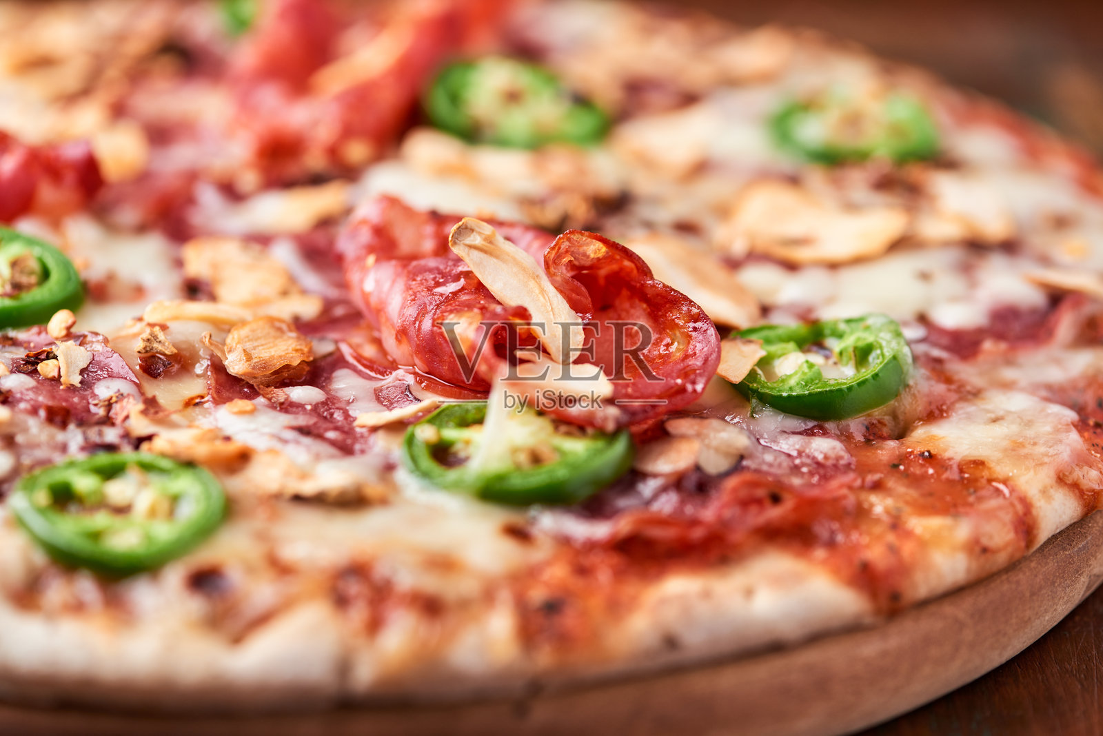 意大利香肠、马苏里拉奶酪和墨西哥胡椒的比萨饼。木质背景。柔和的焦点。照片摄影图片