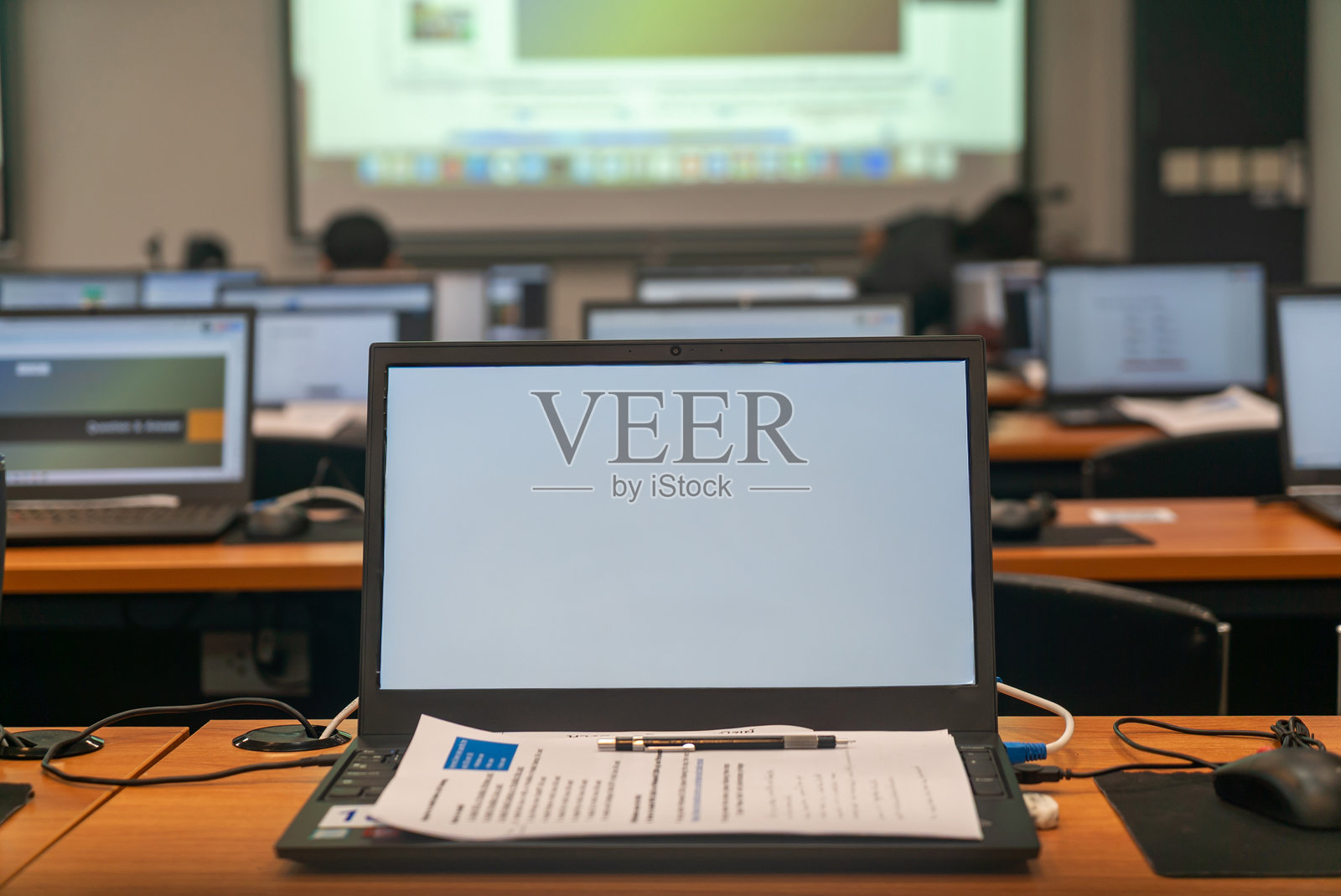 现代教室里空置的笔记本电脑放在桌子上照片摄影图片