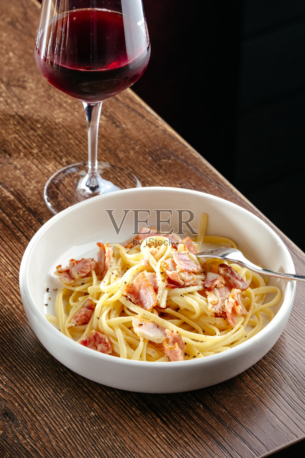 木桌上的意大利碳ara面和一杯红酒照片摄影图片