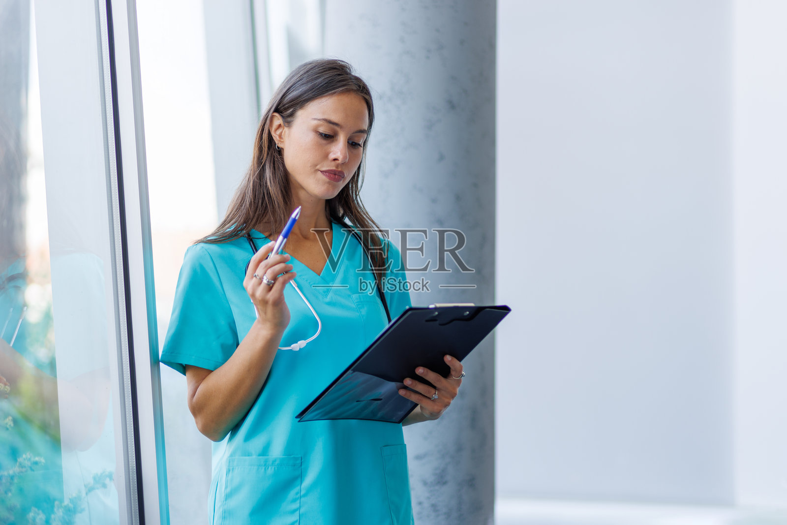 年轻护士在医院走廊阅读病历照片摄影图片