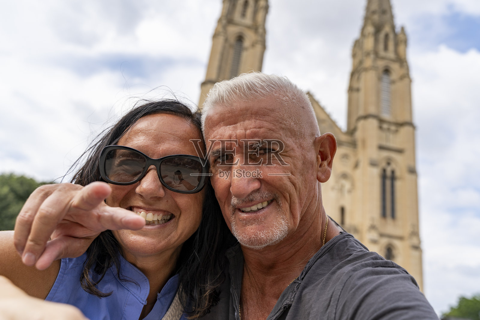 情侣在尼姆市的壮丽大教堂前拍自拍并做出和平手势,享受夏季旅行。照片摄影图片