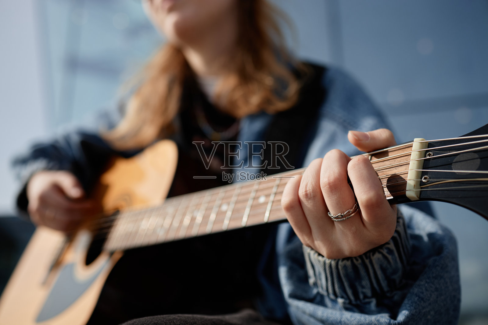 年轻的白人女性在户外练习木吉他的和弦照片摄影图片