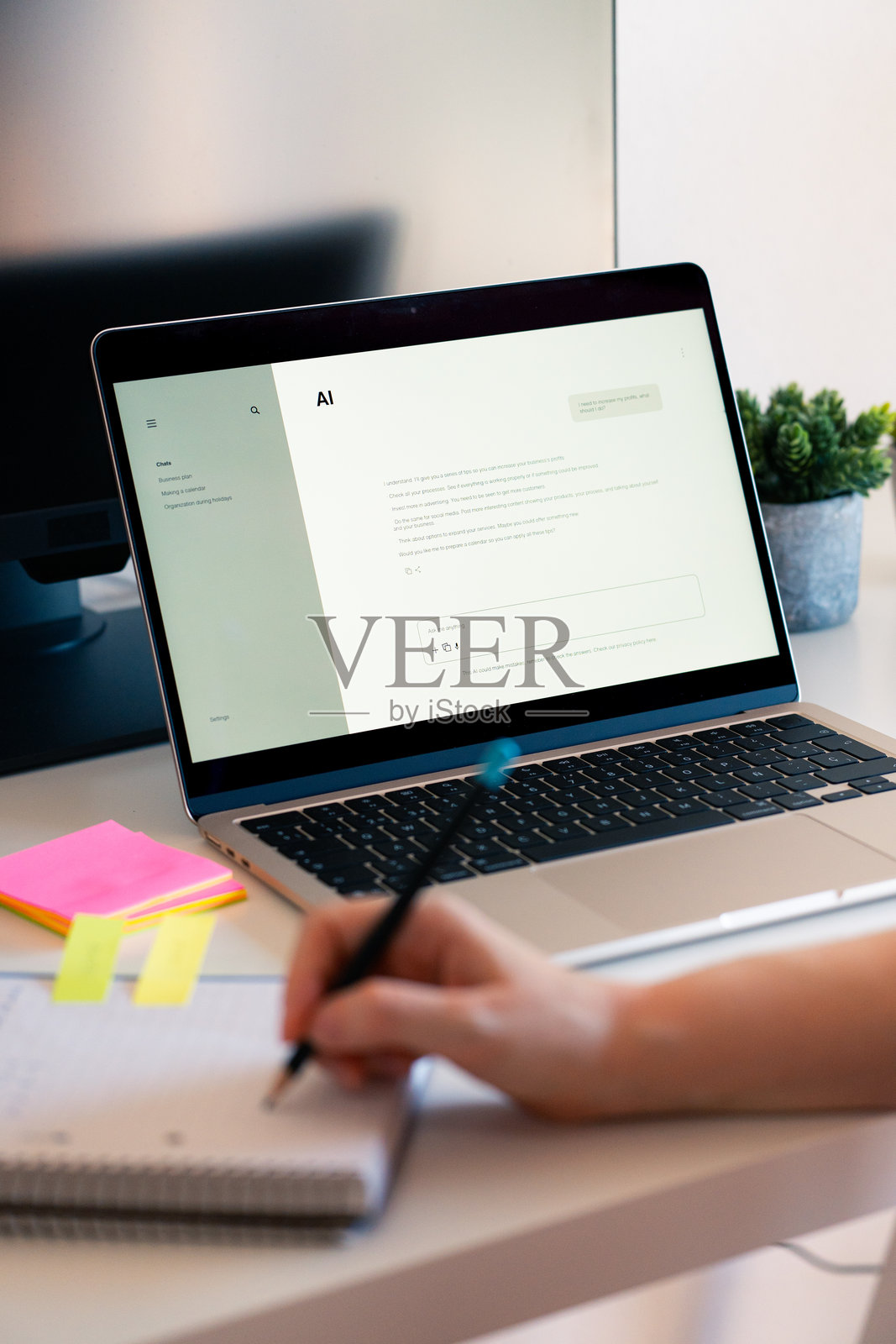 一个人在桌子上使用笔记本电脑与人工智能聊天,同时在五颜六色的便签纸上做笔记。照片摄影图片