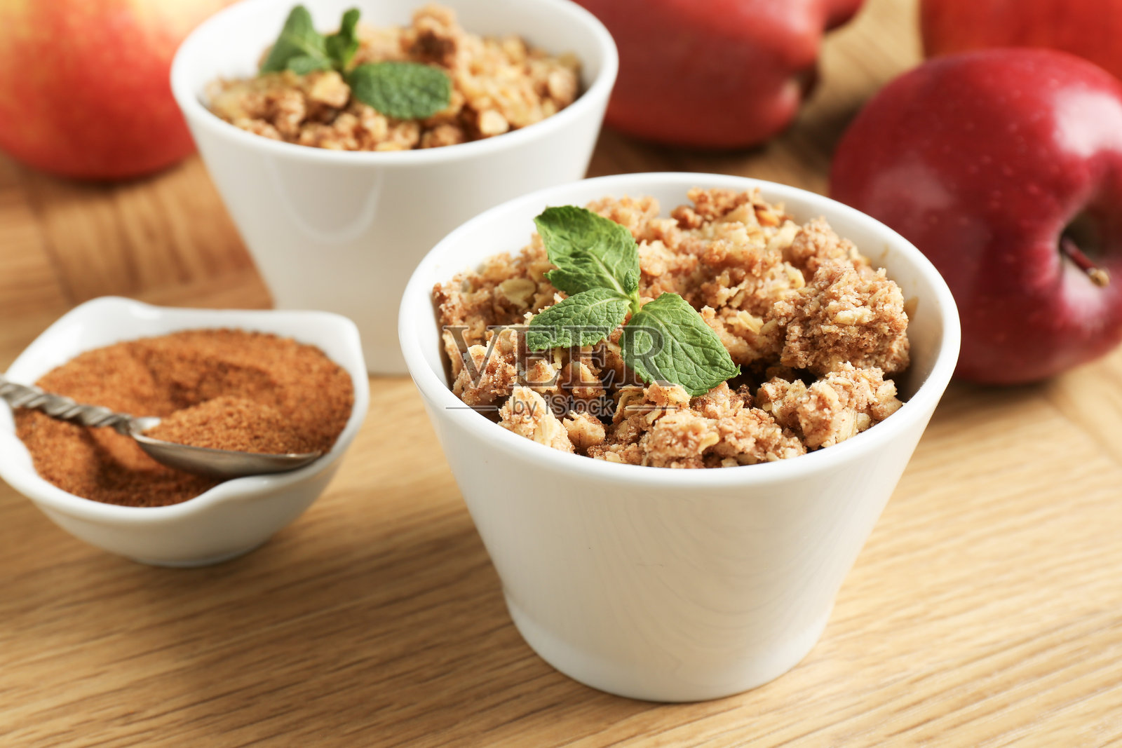 美味的苹果脆饼配薄荷,放在碗里,木桌上有肉桂和新鲜水果,特写镜头照片摄影图片