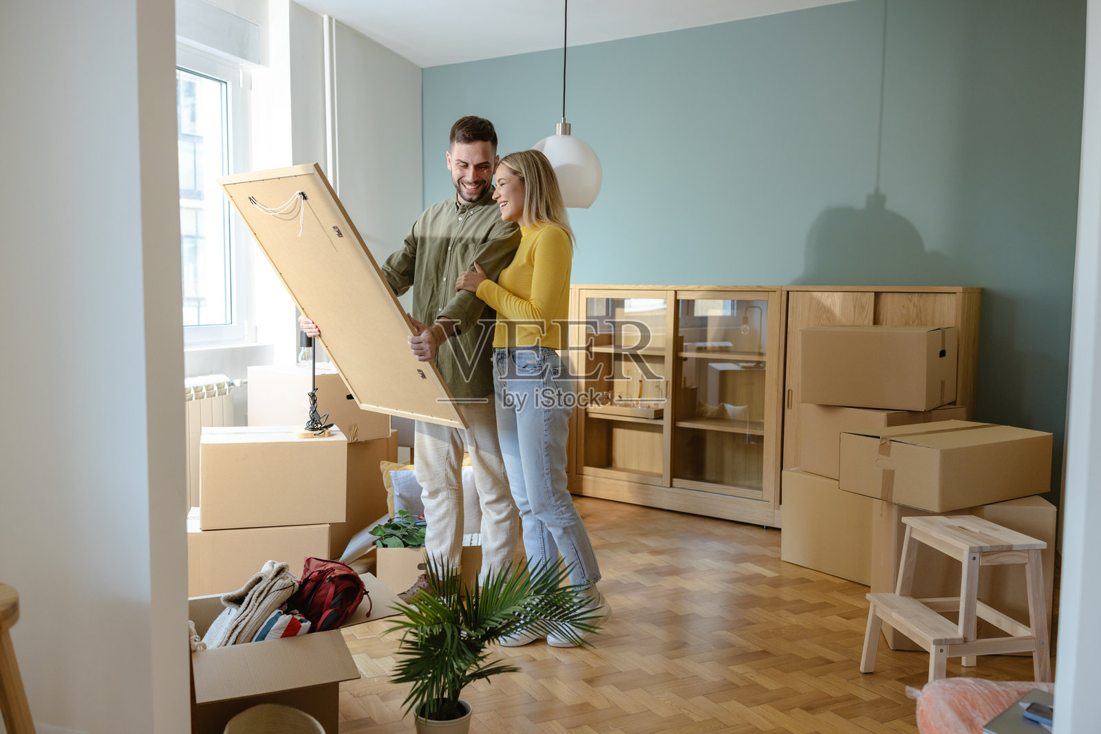 年轻夫妇搬进新现代家,周围堆满了打包箱子照片摄影图片