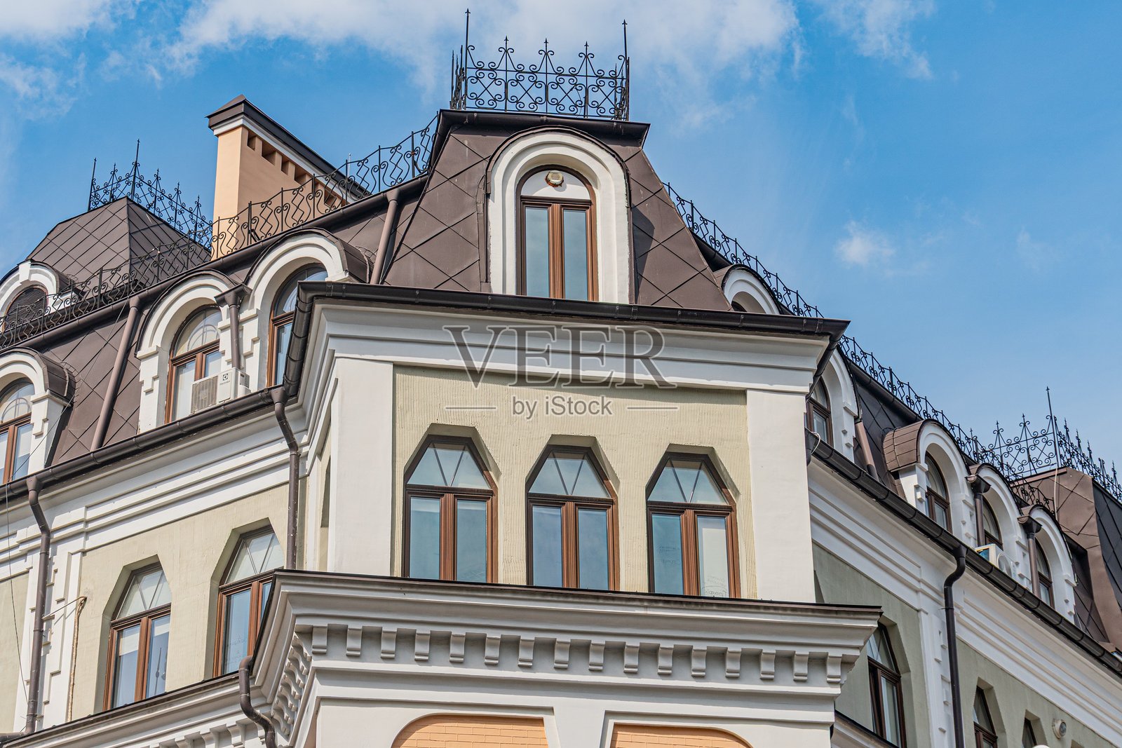 一座浅色的宏伟欧洲建筑,拥有多个窗户立面和华丽的装饰元素,背景是清晰的城市景观。屋顶上有天窗,从高处拍摄。照片摄影图片