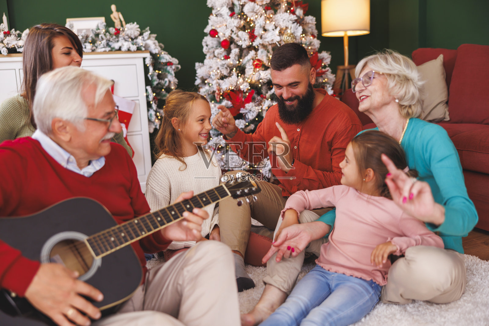 多代家庭在庆祝圣诞节时弹吉他和唱圣诞歌曲照片摄影图片