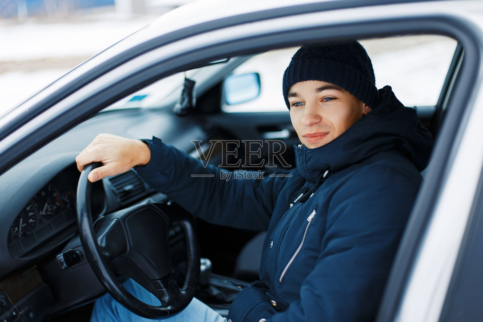 帅气的年轻男子坐在车里,握着方向盘照片摄影图片