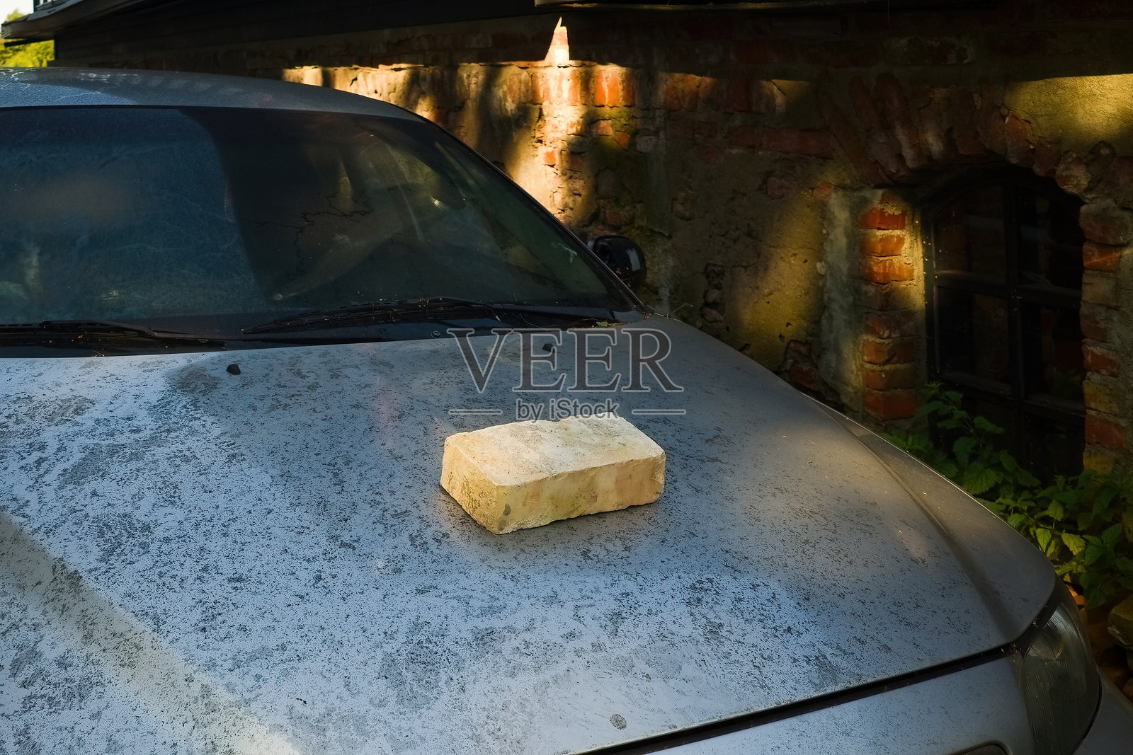 尘土飞扬的汽车引擎盖上的砖块照片摄影图片