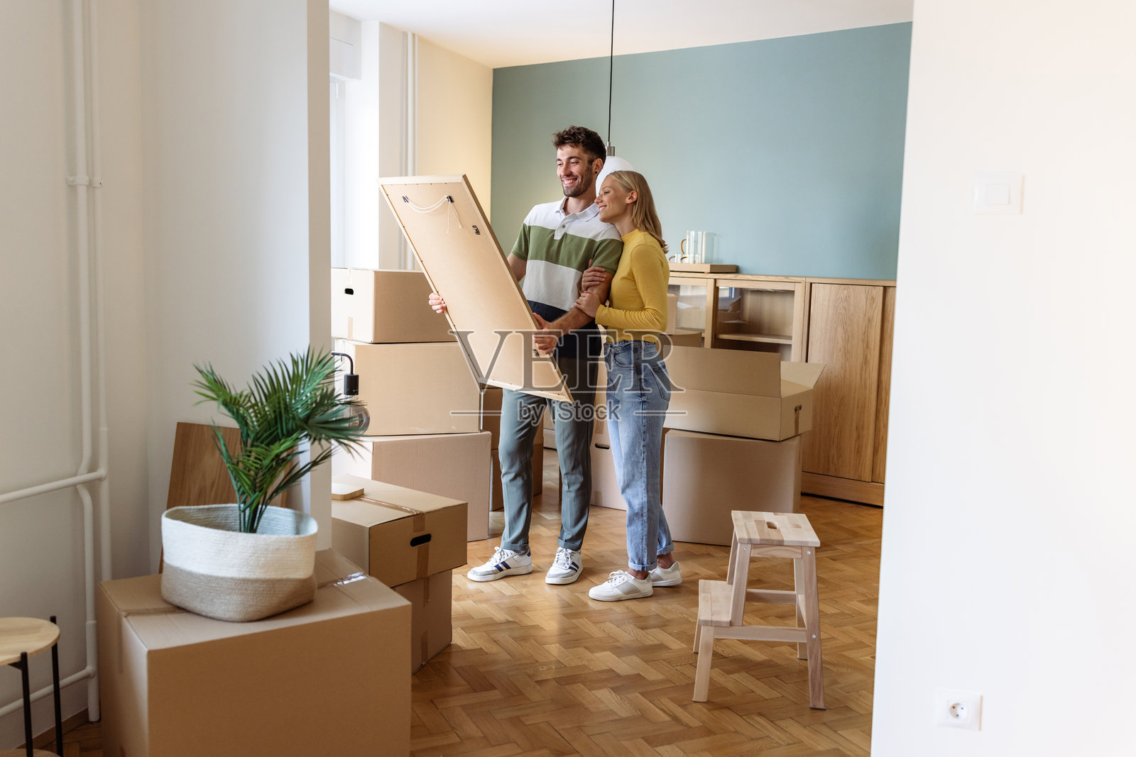 年轻情侣在新家拆箱并一起装饰照片摄影图片