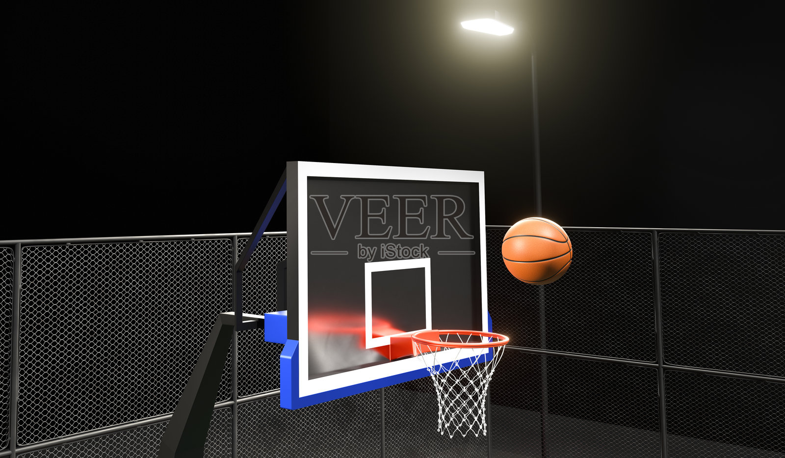 橙色篮球在夜晚的户外篮球场上漂浮在篮筐网之上照片摄影图片