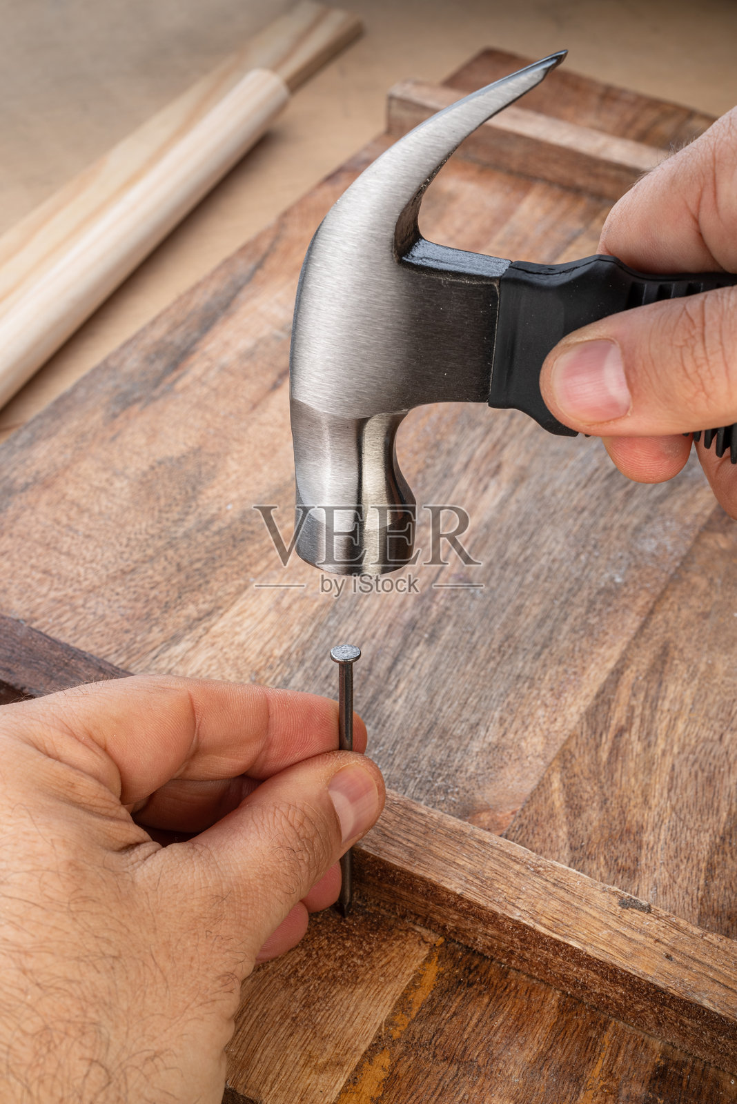 男人的手用锤子在木板上钉钉子。照片摄影图片