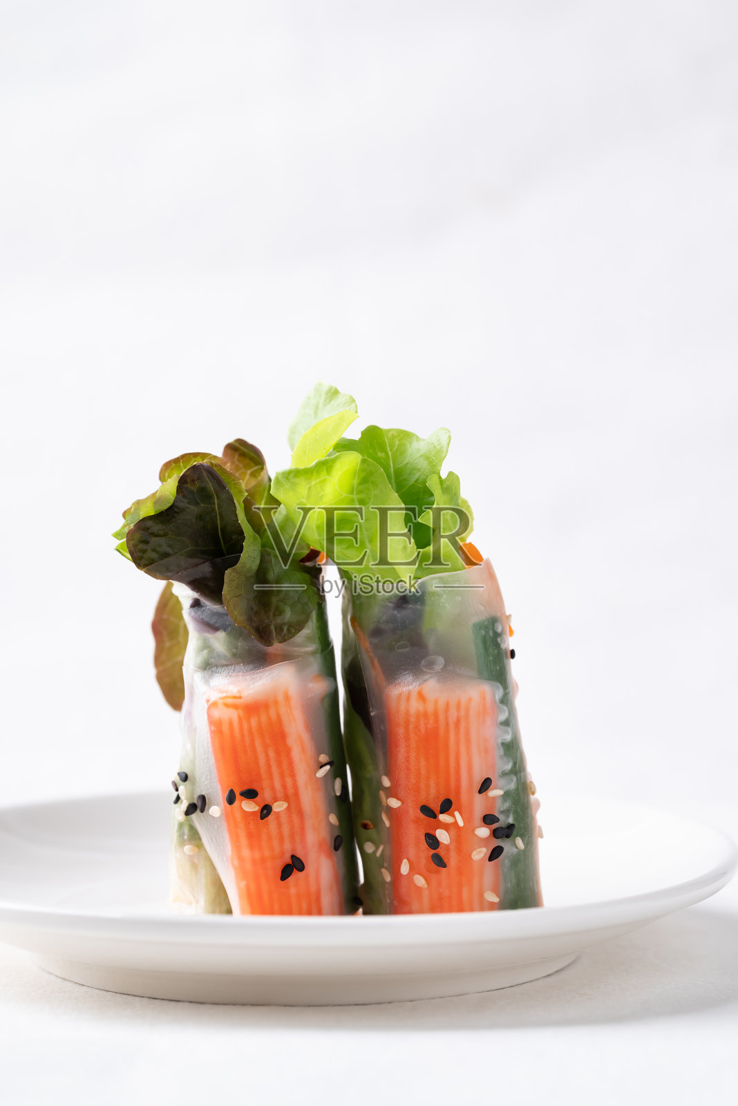 蟹棒、胡萝卜、黄瓜和生菜用米纸包裹的沙拉卷照片摄影图片