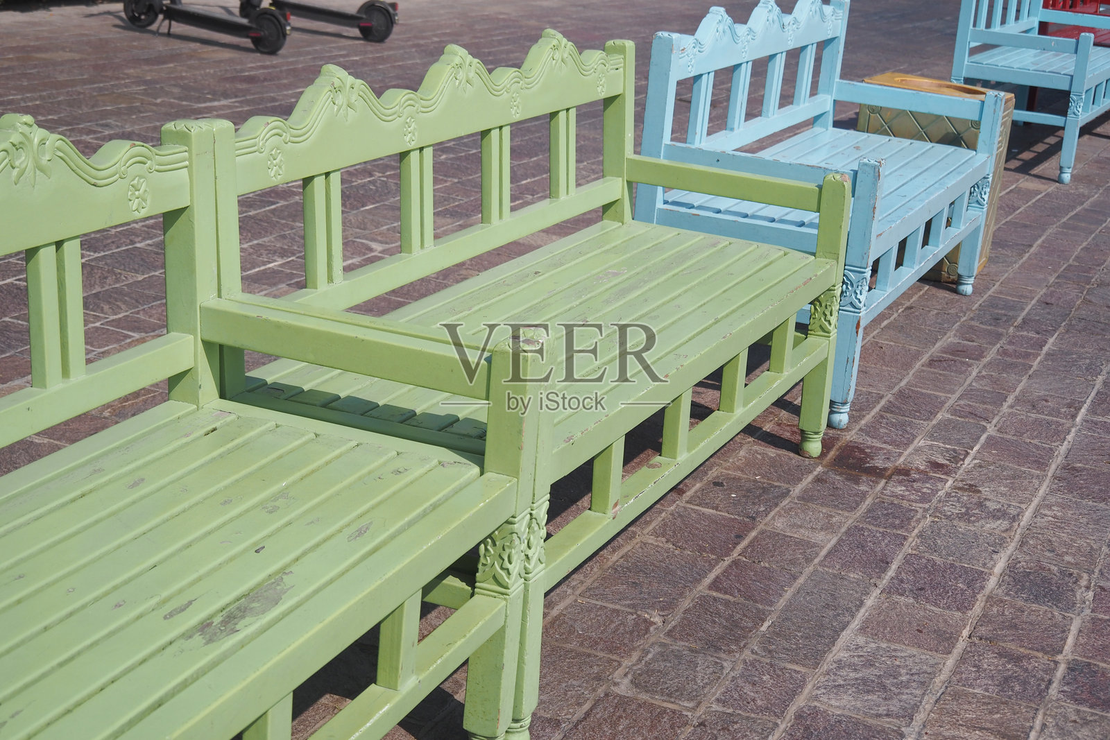 五彩斑斓的木长椅沿着阳光明媚的广场石板路排成一排照片摄影图片