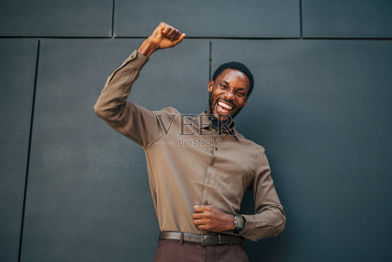 年轻商人庆祝成功,举起拳头。照片摄影图片