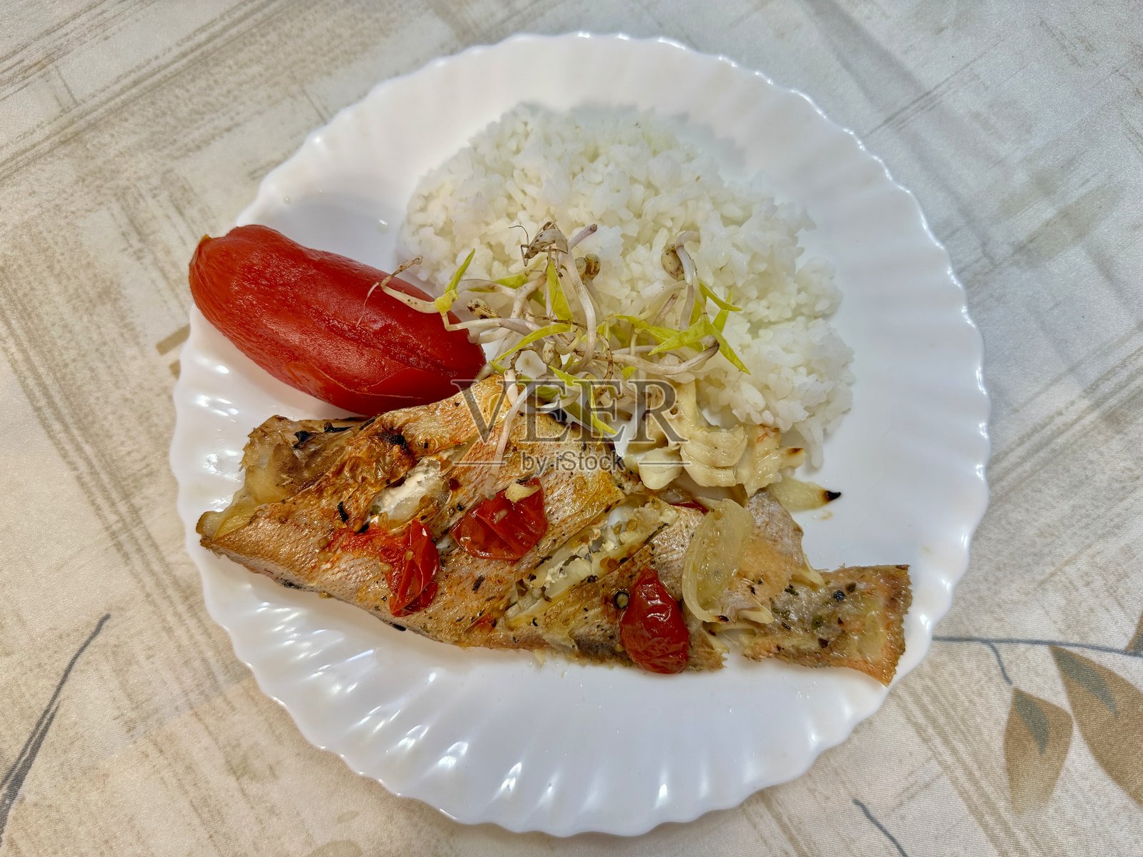白盘上的海鲈鱼配豆芽、米饭和番茄。在家健康饮食。照片摄影图片