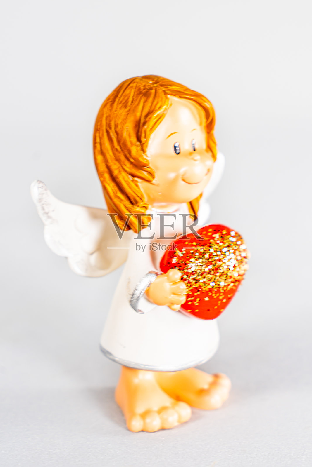 白色背景上的天使雕像。白色背景上的天使小雕像。孤立的陶瓷天使。照片摄影图片