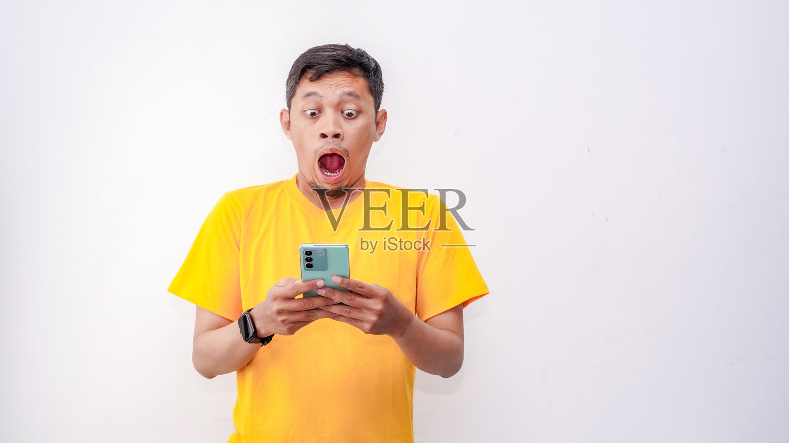 亚洲男子在白色背景下看智能手机时感到震惊照片摄影图片