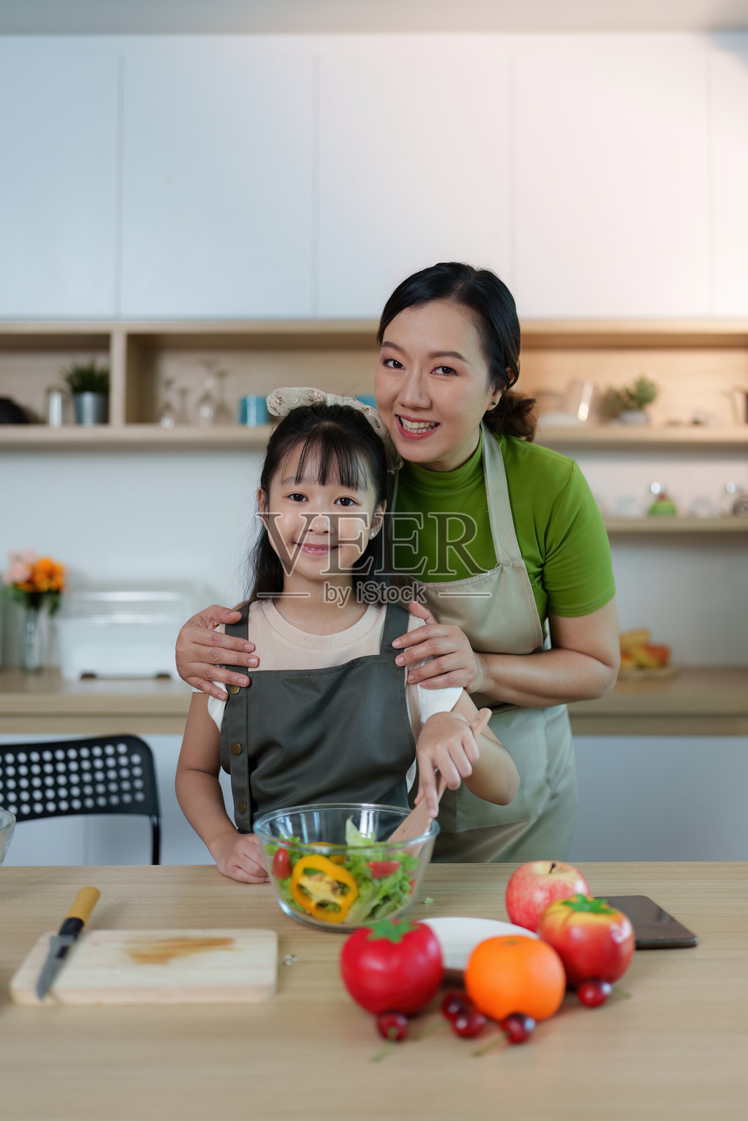 母女一起烹饪。在明亮的厨房里制作健康餐。照片摄影图片