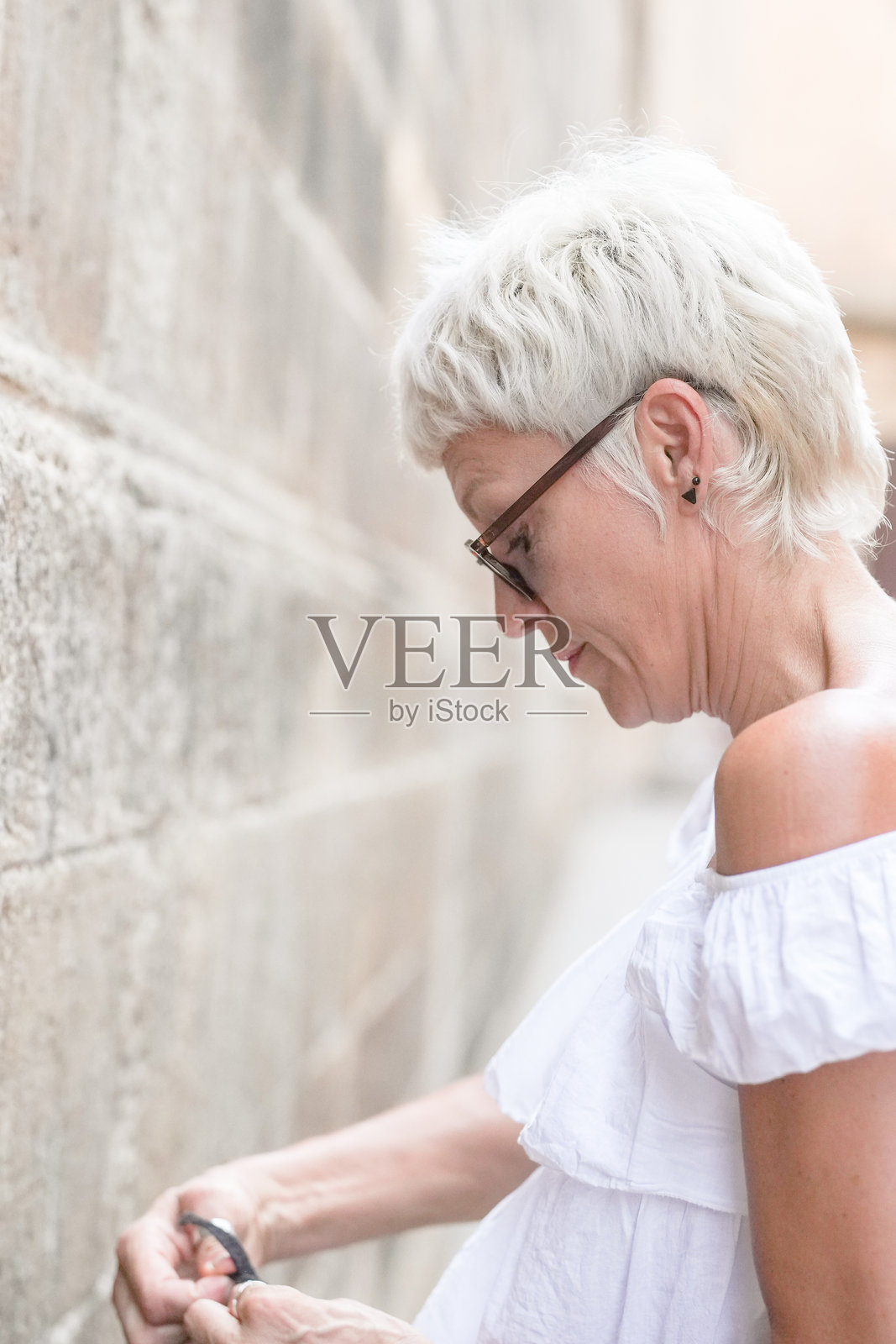 一位短发金发、戴眼镜的女性正在对着镜头微笑。照片摄影图片