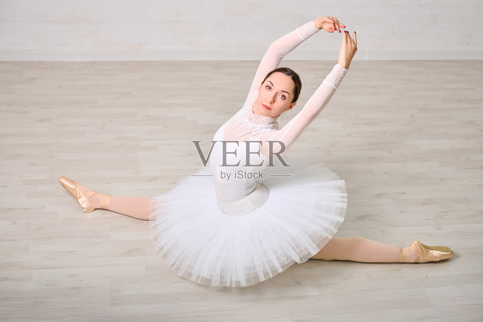 优雅的芭蕾舞者在木地板上劈叉照片摄影图片