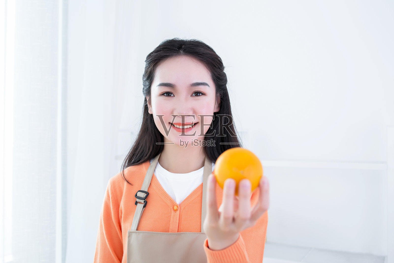 年轻女性微笑着手持一个橙子照片摄影图片